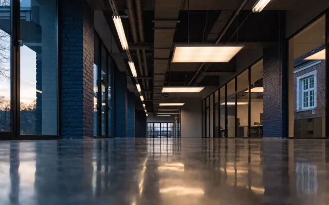 Couloir de bâtiment public au crépuscule en transition d'éclairage fluorescent vers LED, trois tubes anciens remplacés par des panneaux LED visibles